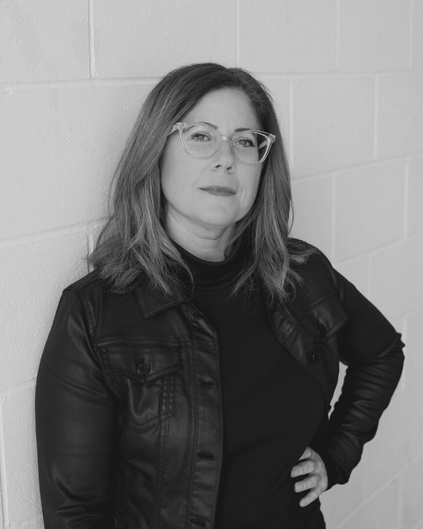 a black and white photo of a woman with glasses and a serious look